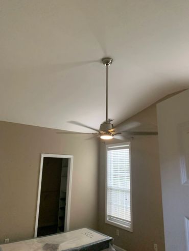 Modern ceiling fan with light in a beige-walled room.