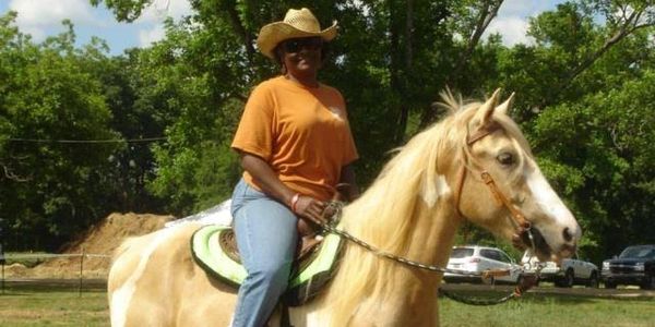 A woman named Brenda Barber riding her palomino paint horse named Skye