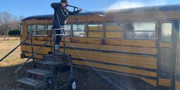 a yellow school bus being pressure washed