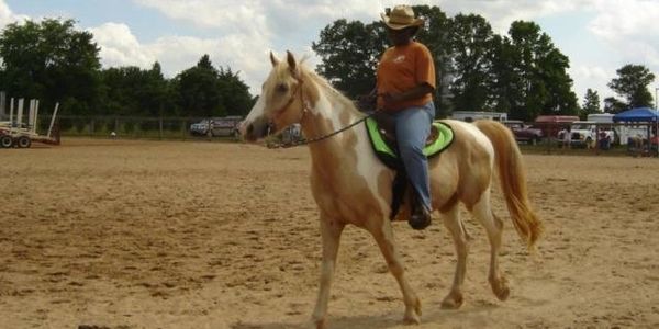 A woman named Brenda Barber riding her palomino paint horse named Skye