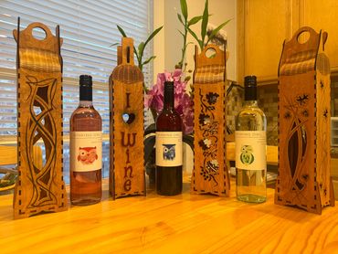 Three Winking Owl wine bottles with decorative wooden wine holders on a wooden table.