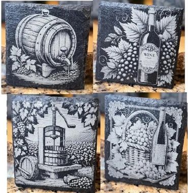 Four black stone blocks engraved with vintage wine and grape designs.