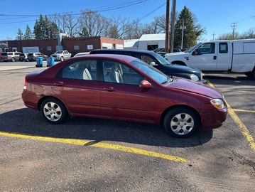 Red sedan parked in a parking lot on a sunny day.