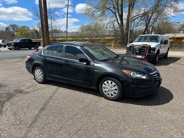 Black sedan parked in a lot on a sunny day.