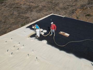Two workers installing a new spray foam roof in Vista, California