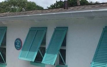 Poolside view with turquoise window shutters and lounge chairs.