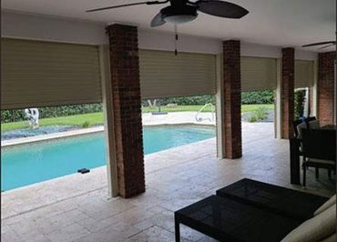 Covered patio with ceiling fans overlooking a swimming pool.