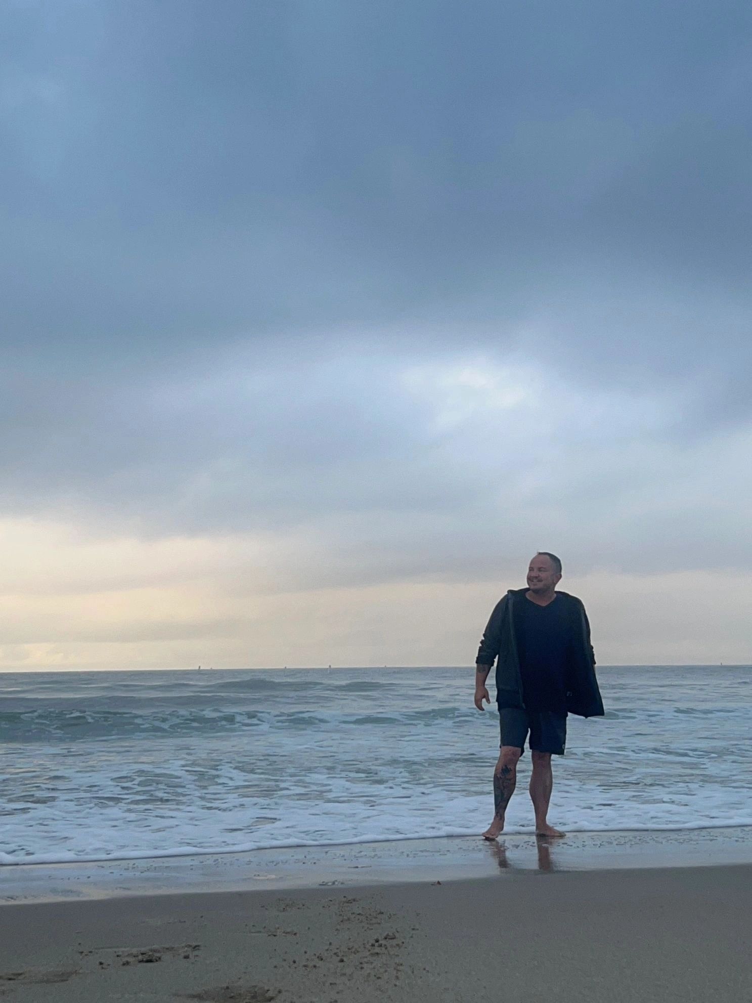 Nik Goodyear standing barefoot on a beach along the Pacific coast in Los Angeles.