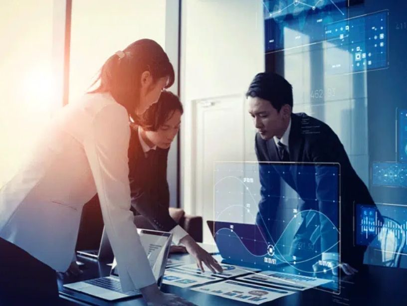 Three professionals analyzing data with digital charts and futuristic interfaces.