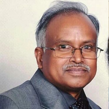 Portrait of an elderly man with glasses in a gray suit.
