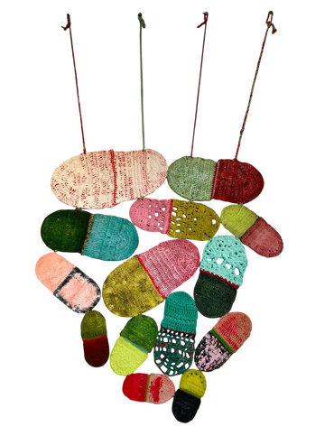 Colorful crocheted capsules hanging by strings in various sizes and patterns.