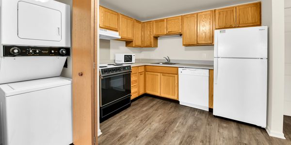 Modern kitchen with wooden cabinets, kitchen appliances and stacked washer-dryer unit.