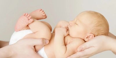 Newborn baby peacefully sleeping in gentle adult hands.