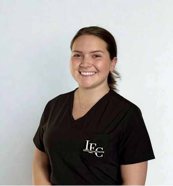 Smiling woman in a black scrub top with 'Interior Fresh Cleaning' logo.