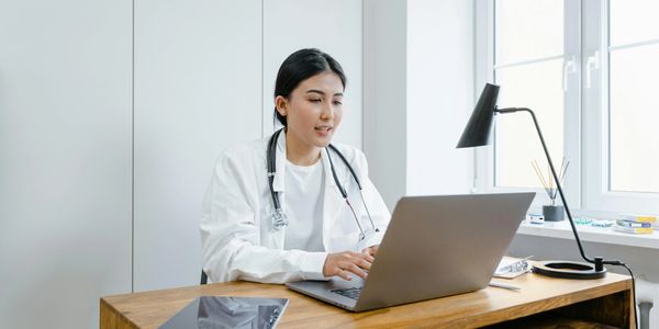 Female doctor working on a laptop in a bright office.