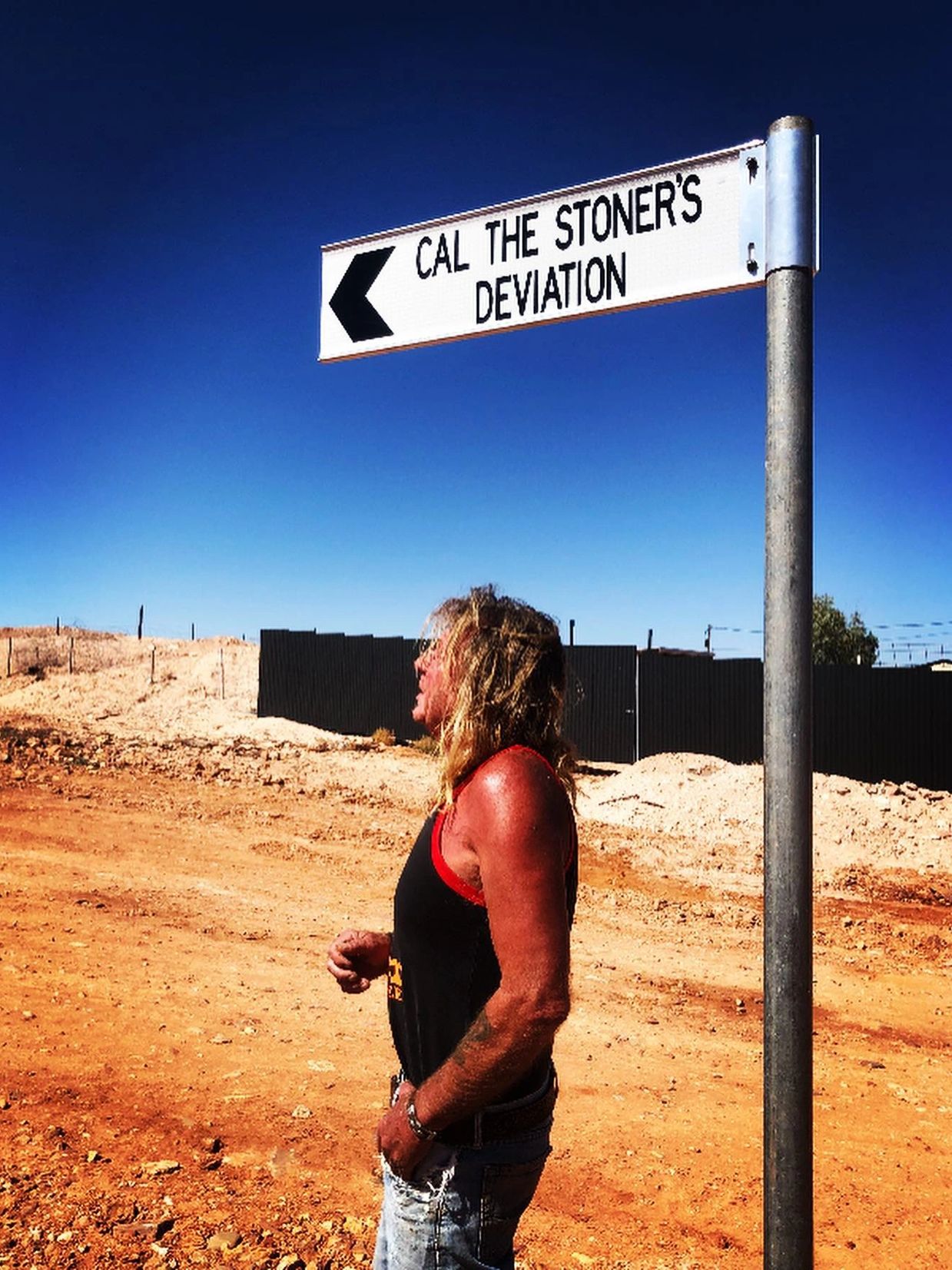 Cal the Stoner's studio has it's own street sign in Andamooka. Cal standing under the sign.
