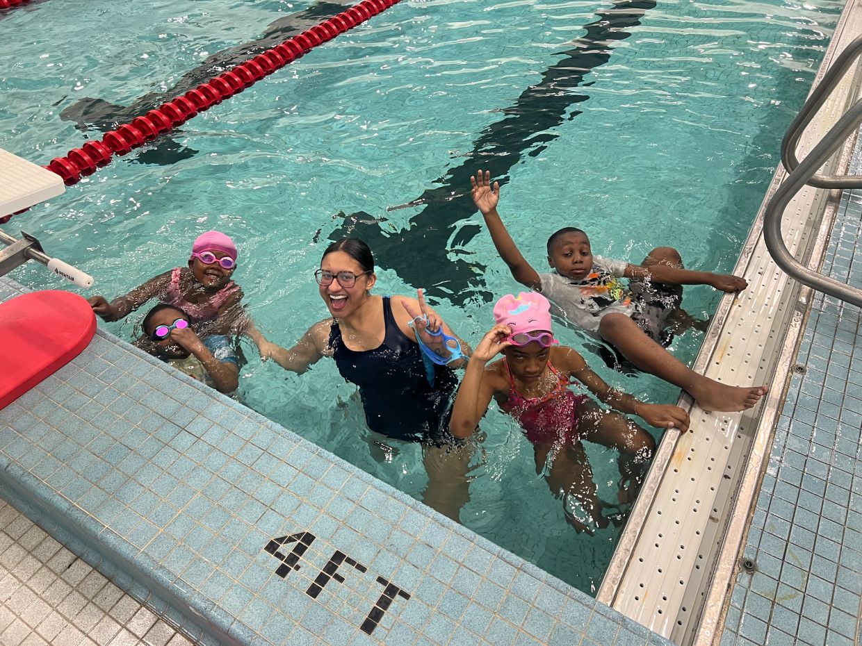 Group of kids and an instructor in a swimming pool.