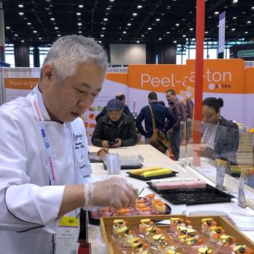 Chef preparing bite-sized appetizers at a food exhibition booth.