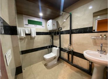 Modern bathroom with toilet, sink, water heater, and black marble accents.
