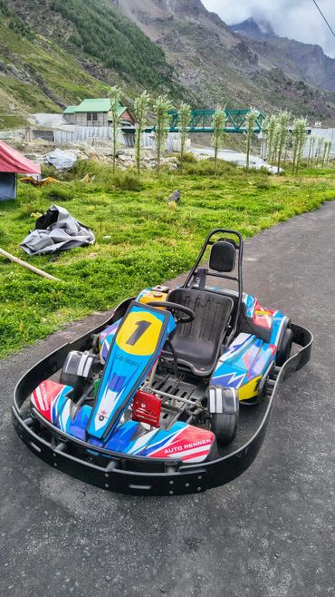 Colorful go-kart parked on a mountain road with scenic backdrop.
