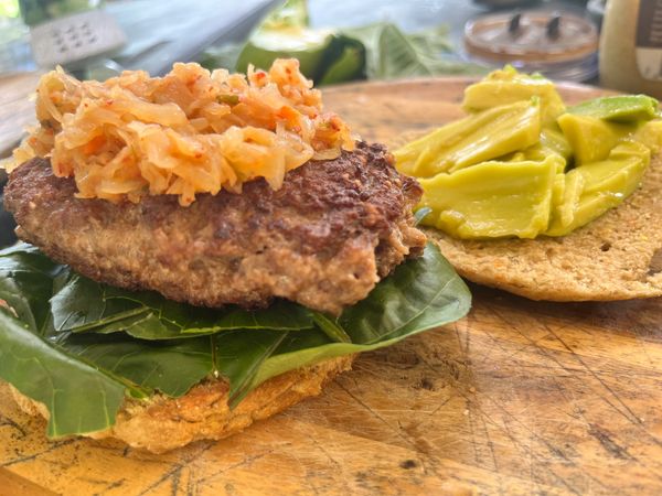 A 100% farm fresh beef burger patty served with an avocado, homemade bun, and sauerkraut.