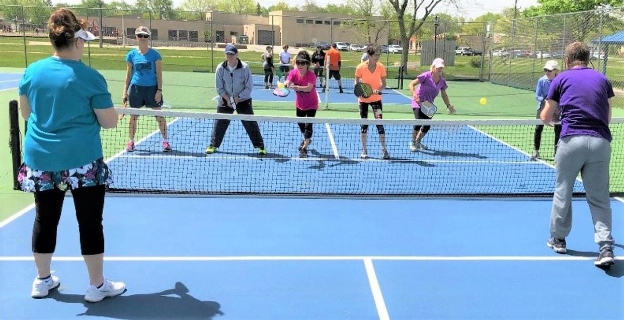 Group of people playing pickleball on an outdoor court.
