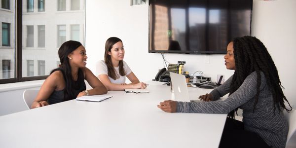 Three women at a table in the middle of a meeting