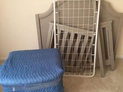 Disassembled crib parts leaning against a wall on carpet.