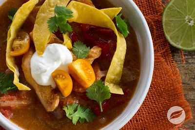Bowl of chicken tortilla soup with sour cream and fresh cilantro.