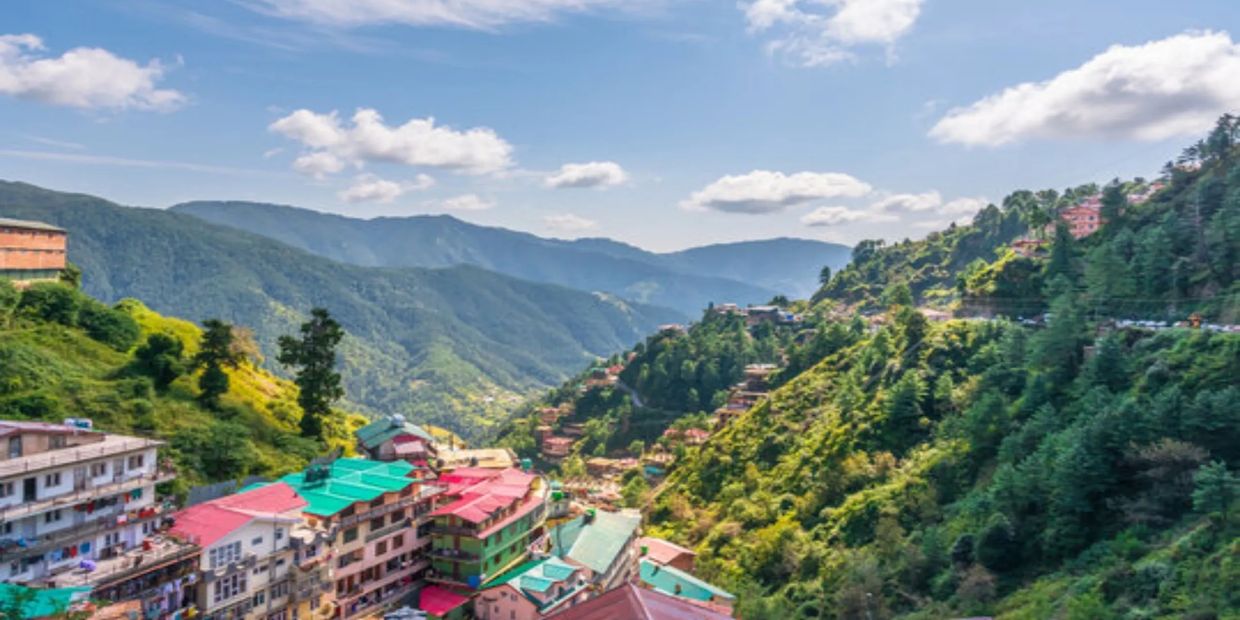 A vibrant hillside town surrounded by lush green mountains under a blue sky.