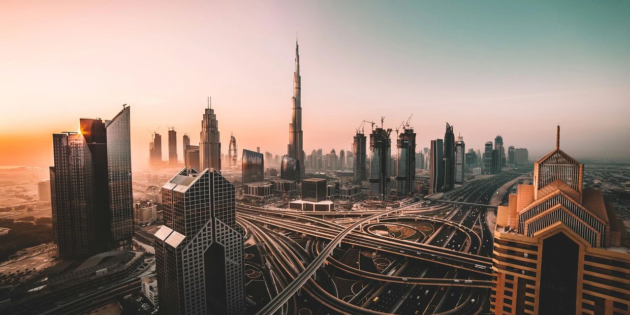 Sunset over a sprawling cityscape with towering skyscrapers and intricate highways.