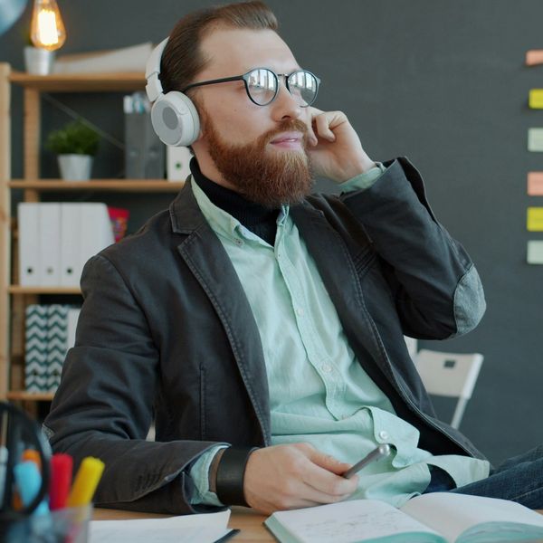 Man with glasses and headphones working at a desk.