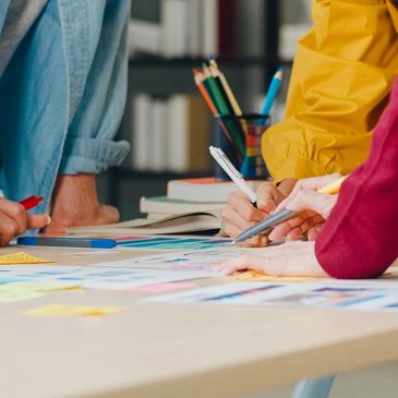 People collaborating over papers and notes on a table with coffee nearby.