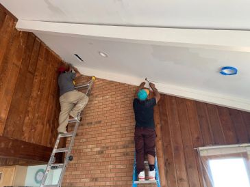 Painting and remodeling crew working together on an interior ceiling