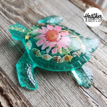 Handcrafted blue resin sea turtle featuring a real pressed flower centerpiece and natural seashell a