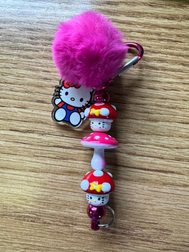 Hello Kitty-themed keychain with pink pom-pom and mushroom charms.