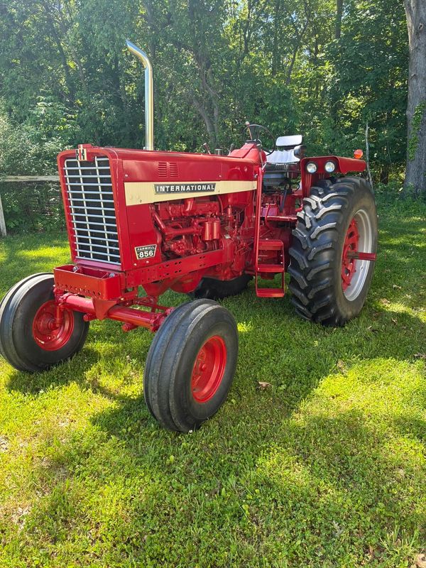 Bright red International Farmall 856 tractor parked on green grass.