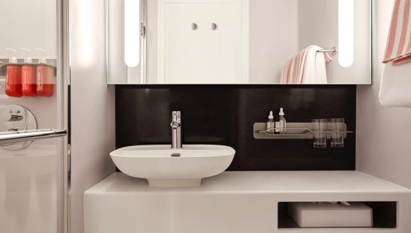 Modern bathroom sink with minimalist design and black backsplash.