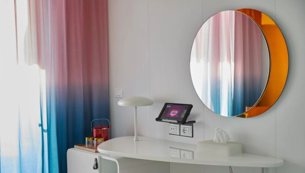 Modern white desk setup with colorful curtains and round mirror.