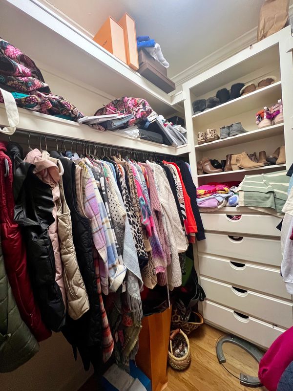 A colorful, organized closet filled with sweaters, shoes, and storage boxes.