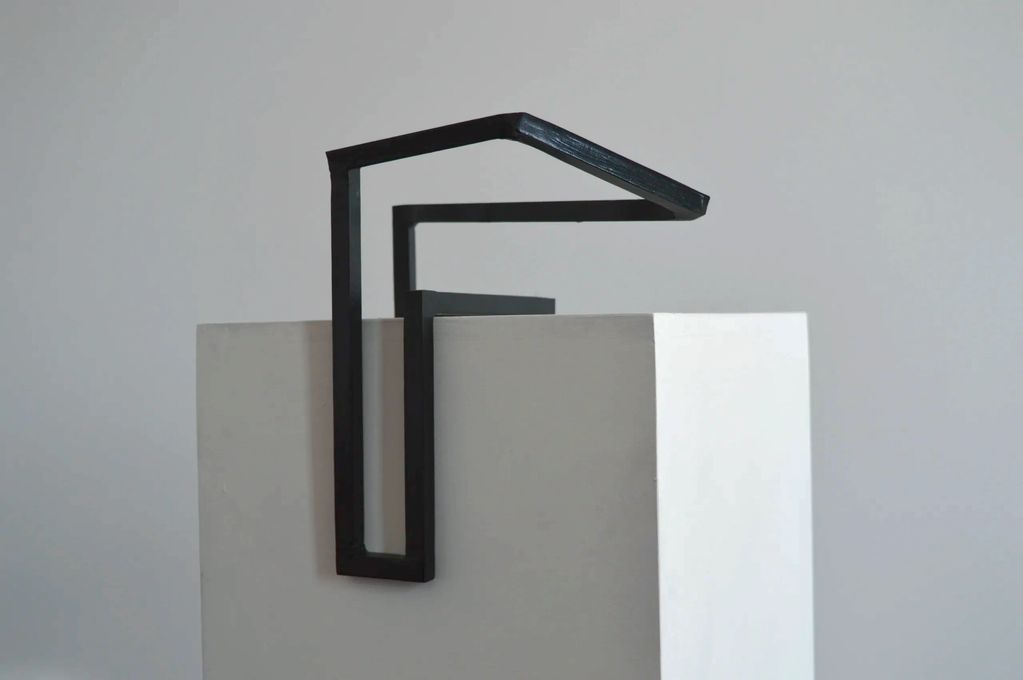 A dark green shape of square steel bars on top and in the middle of a white plinth.