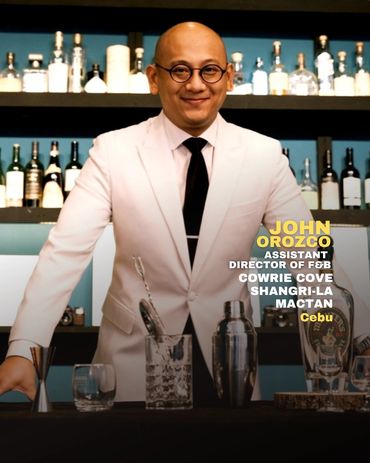 John Orozco, assistant director in a white suit behind a bar.
