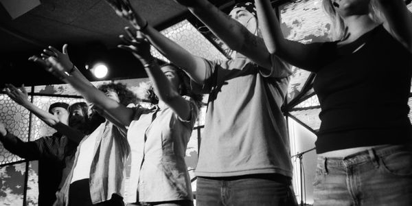 Group of people raising their hands, possibly in a performance or celebration.