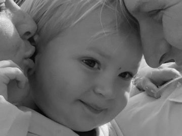 A tender moment between a child and two adults sharing affection.