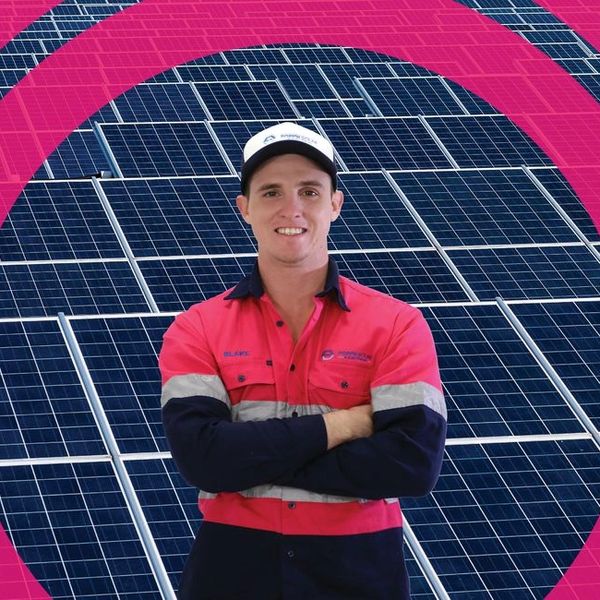 Worker standing confidently in front of solar panels.