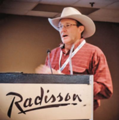 Man in hat speaking publicly.