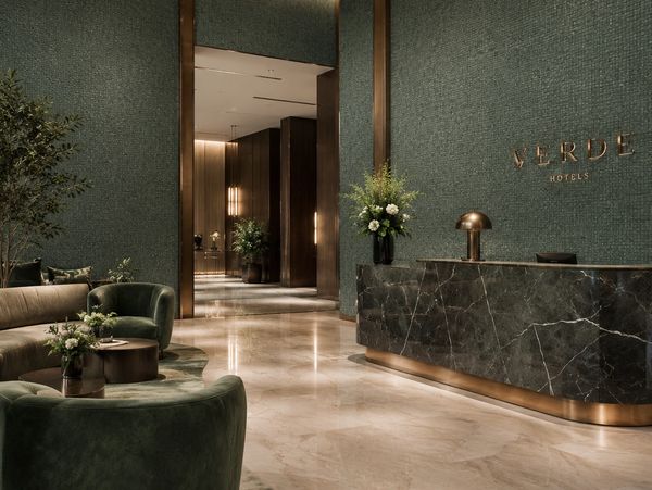 Elegant hotel lobby with green accents and marble reception desk.