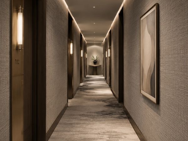 Modern hotel hallway with soft lighting and carpet.