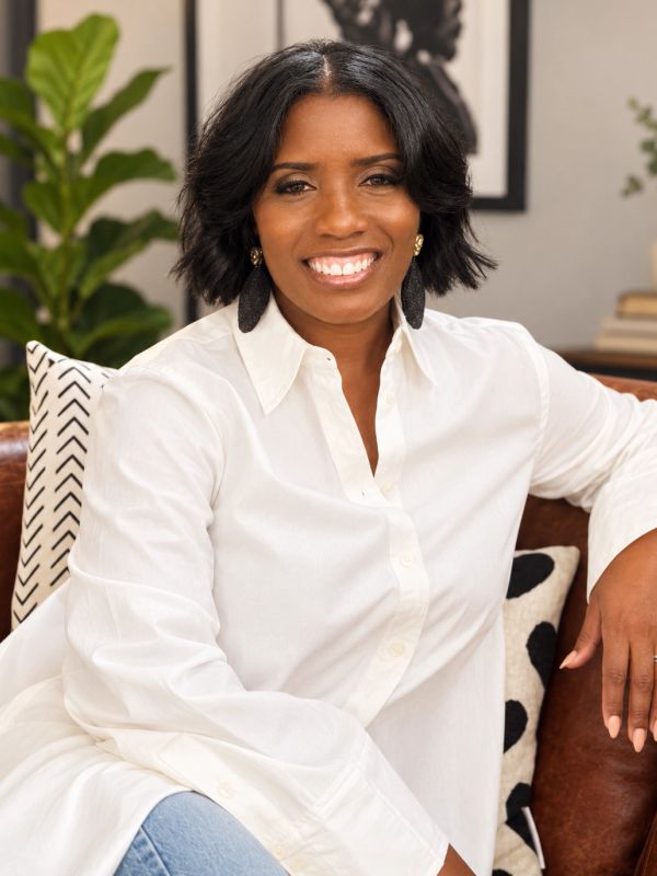 Smiling woman in white shirt sitting on a couch.