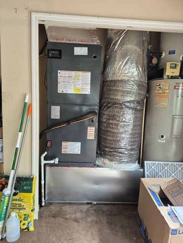 5 ton Goodman air handler installed on a metal return box in a garage.